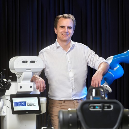 Professor Jan Peters mit verschiedenen Robotern