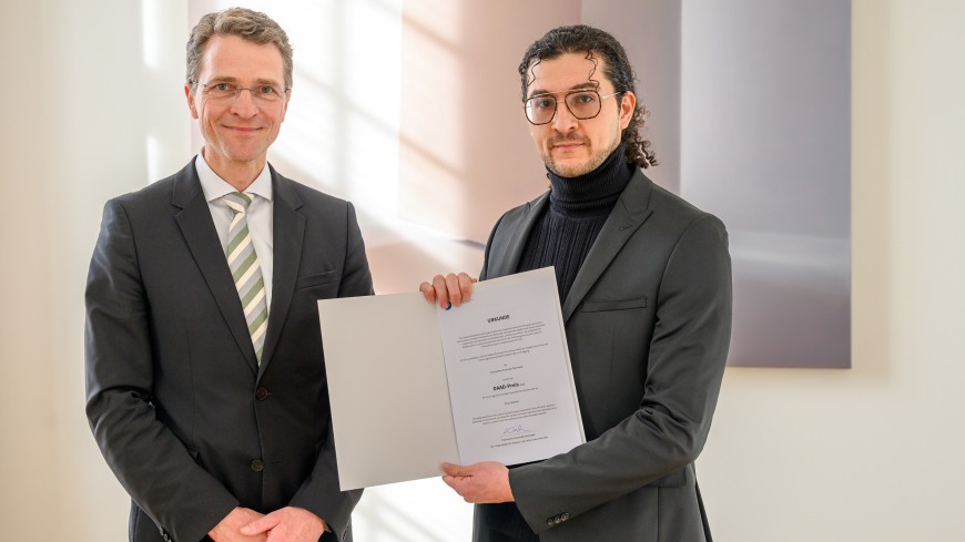 Vizepräsident Heribert Warzecha und DAAD-Preisträger Omar Dwedary schauen in die Kamera.