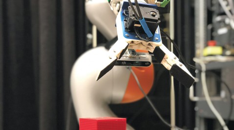 Ein Roboterarm sortiert kleine Klötze.