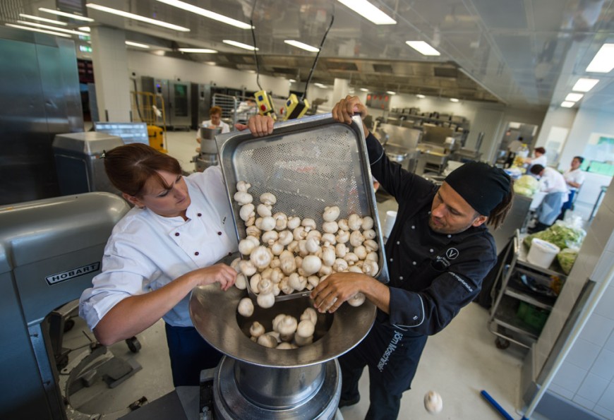 Koch Björn Moschinski und eine Mitarbeiterin des Studentenwerks Darmstadt schütten Champignons in ein Küchengerät. Bild: Andreas Arnold