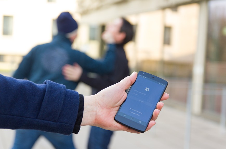 Symbolbild: Im Vordergrund hält eine Hand ein Smartphone, im Hintergrund kämpfen zwei Gestalten. Bild: Silke Paradowski