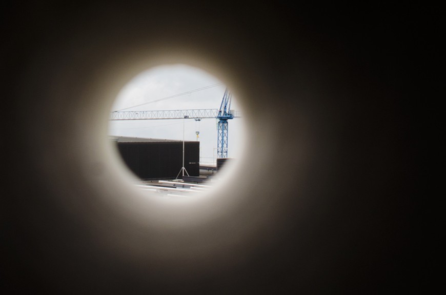 Blick durch eine schwarze Röhre auf einen Baukran. Bild: Patrick Bal