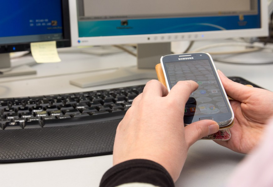 Eine Frau benutzt ihr Smartphone am Arbeitsplatz. Bild: Patrick Bal