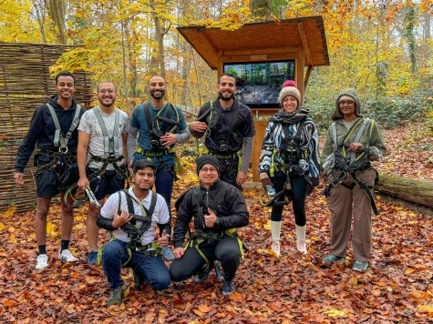 Master's students from TU Darmstadt and their MasterPlus buddies enjoying a day of adventure in a high ropes course. The image captures the group during one of the social events of the MasterPlus programme. The participants are wearing safety gear and posing in a picturesque autumn landscape, surrounded by colorful leaves and trees. This photo highlights the community spirit and hands-on experiences offered by the MasterPlus programme.