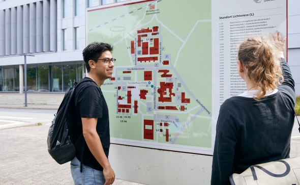 Students at Campus Lichtwiese looking at a map of the Campus. / Zwei Studierende an einer Karte am Campus Lichtwiese.
