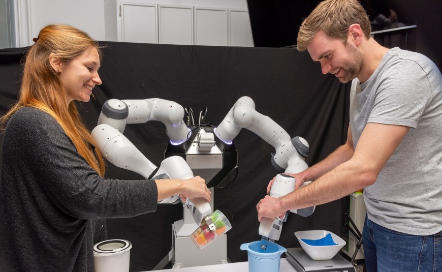 Zwei Studierende der TU Darmstadt, die einen Roboter bedienen.