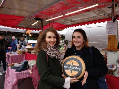 Zwei Frauen auf dem Markt, die einen Käselaib halten / Two females at the market holding the whole cheese wheel