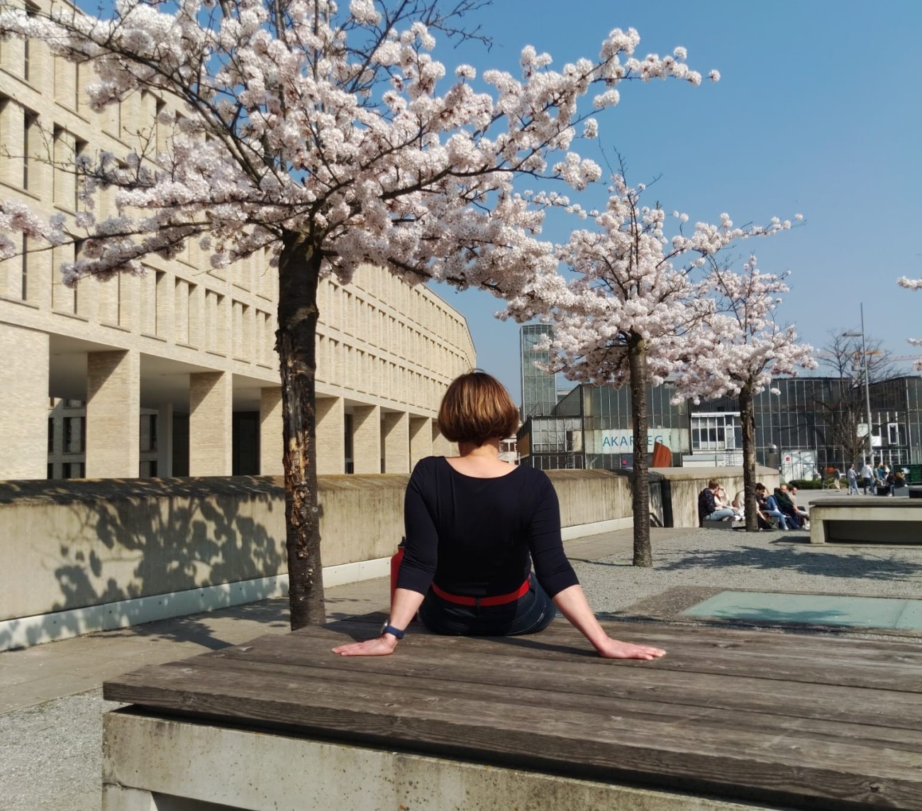 #studentsofTUdarmstadt, Back to Campus: Studentin im Innenhof der TU Darmstadt, Bänke und Kirschblüten. // #studentsofTUdarmstadt, Back to Campus: Student in the courtyard of the TU Darmstadt, benches and cherry blossoms