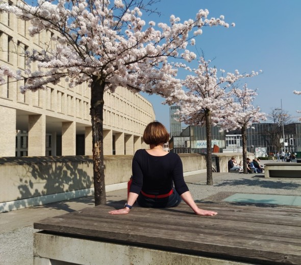 #studentsofTUdarmstadt, Back to Campus: Studentin im Innenhof der TU Darmstadt, Bänke und Kirschblüten. // #studentsofTUdarmstadt, Back to Campus: Student in the courtyard of the TU Darmstadt, benches and cherry blossoms