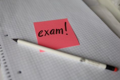 Stift und Notizzettel "exam!" auf Schreibblock. // Pen and note "exam!" on writing pad. 