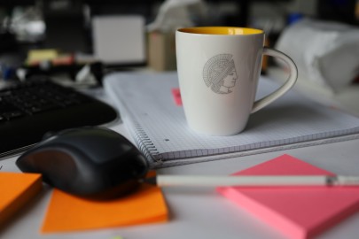 Kaffetasse, Maus und Arbeitsmaterialien auf Schreibtisch. // Coffee cup, mouse and work materials on desk. 