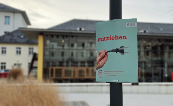Plakat mit Text "mitziehen" vor auf TUDa-Campus.